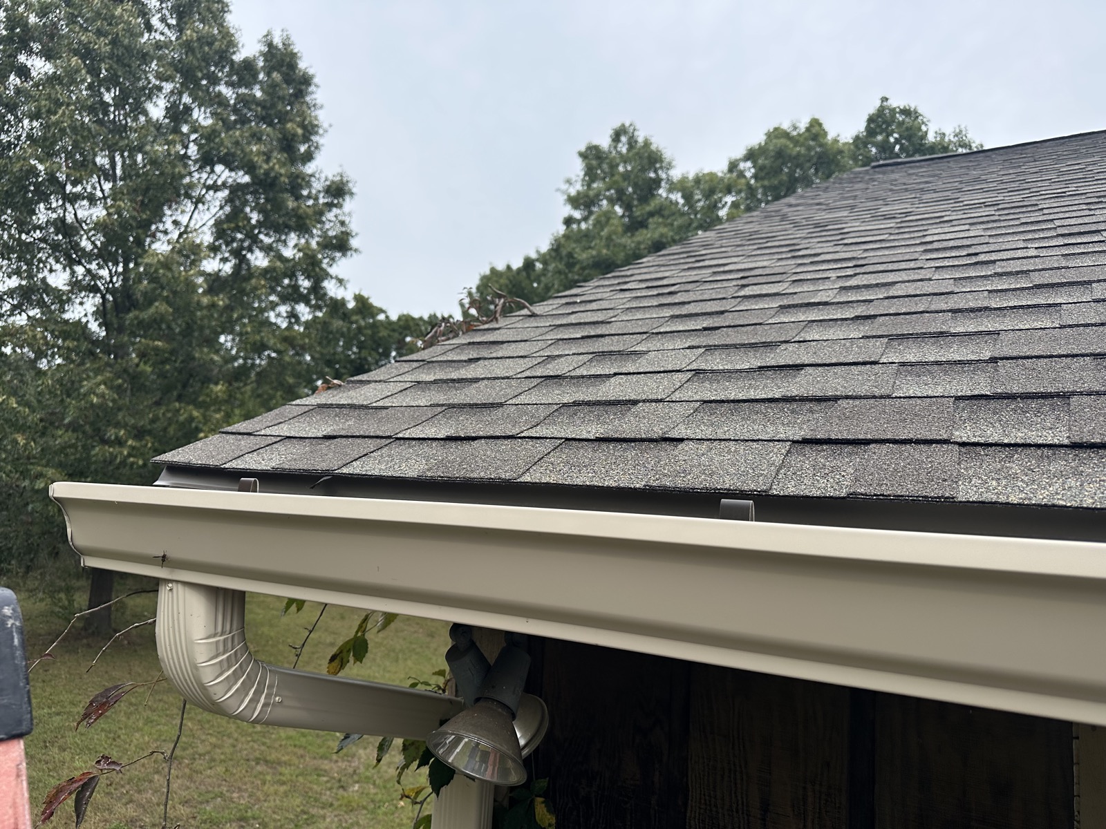 Gutter and downspout along a shingled roof